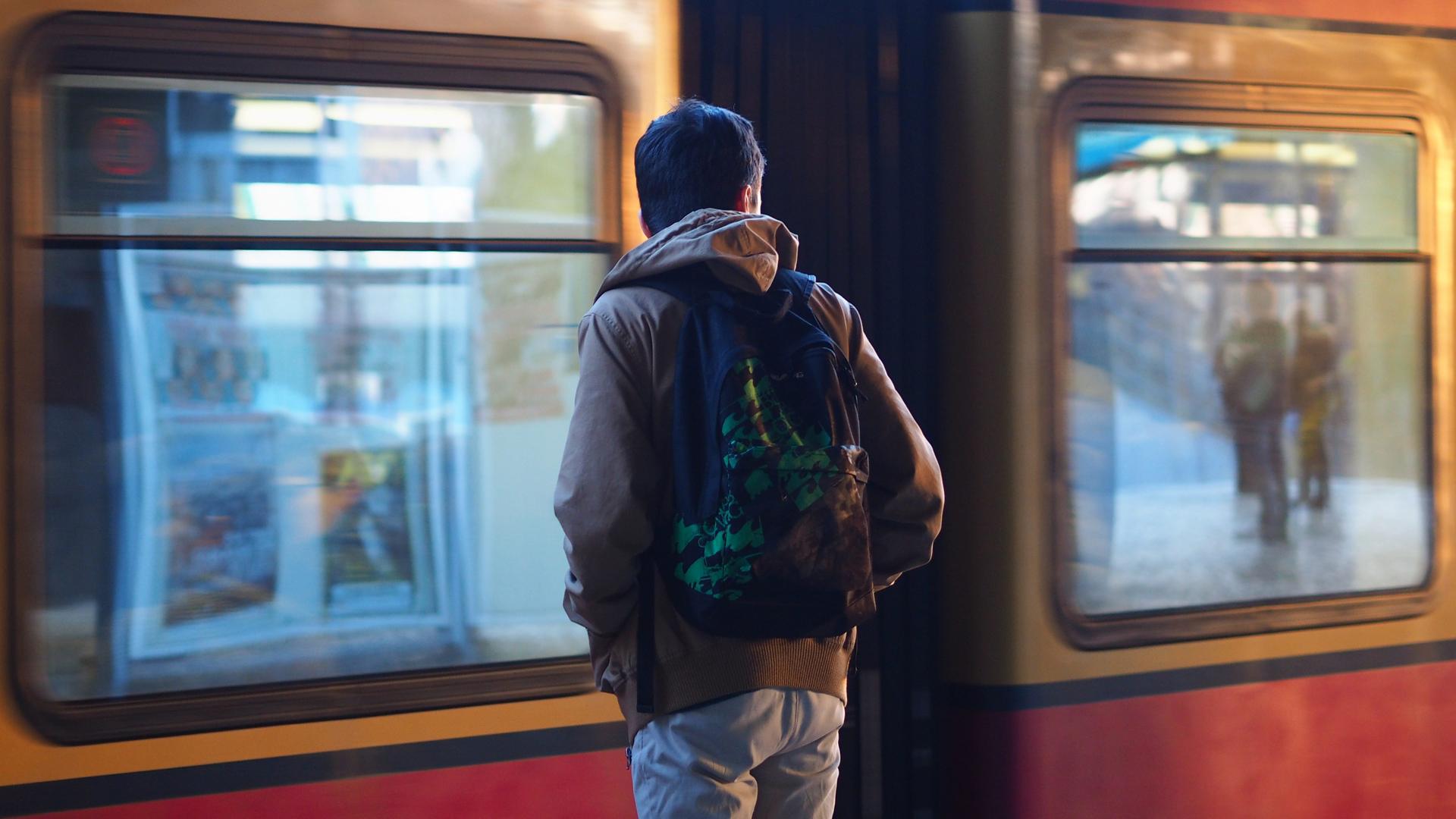 Ein junger Mann mit einem Rucksack steht auf einem S-Bahn-Gleis.