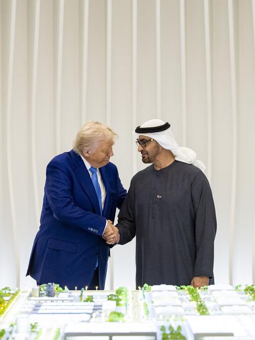 Donald Trump und Mohammed bin Zayed Al Nahyan stehen bei einem offiziellen Empfang vor einer Flagge der USA und der VAE vor einem Architekturmodell. Donald Trump und Mohammed bin Zayed Al Nahyan stehen bei einem offiziellen Empfang vor einer Flagge der USA und der VAE vor einem Architekturmodell.