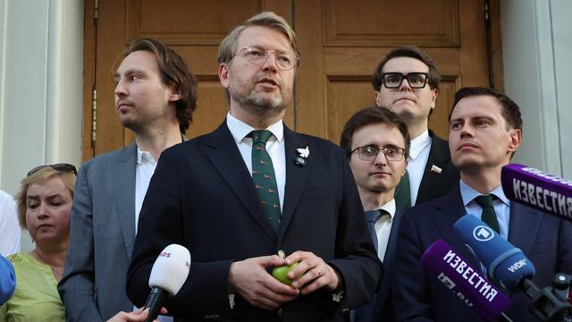 Nikolaj Rybakow steht vor dem Gerichts-Gebäude in Moskau. In der Hand hält er einen grünen Apfel. Neben ihm stehen mehrere andere Partei-Mitglieder.
