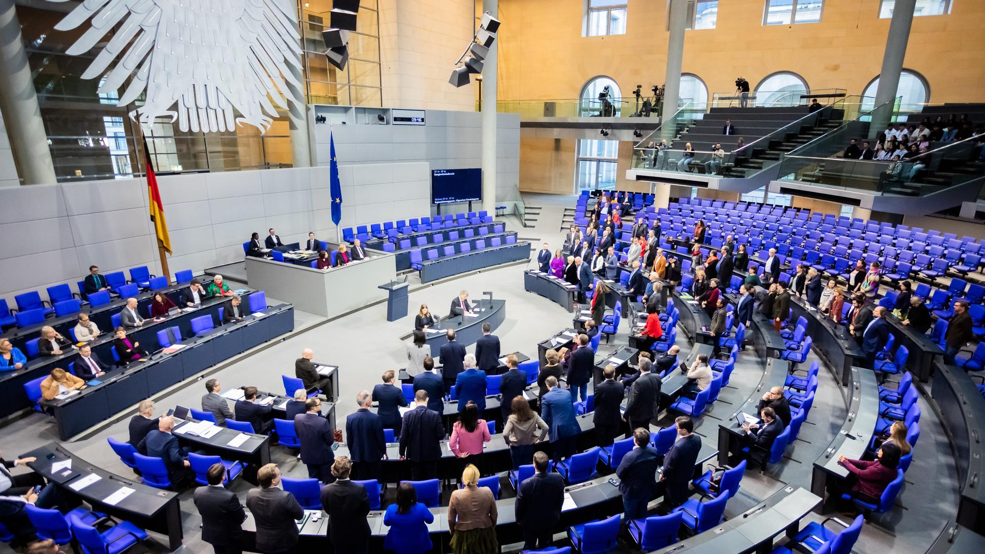 Der Plenarsaal des Bundestages mit Mitgliedern des Deutschen Bundestages, die auf den halbkreisförmig angeordneten blauen Stühlen sitzen. Im Hintergrund an der Wand sieht man den Bundesadler.