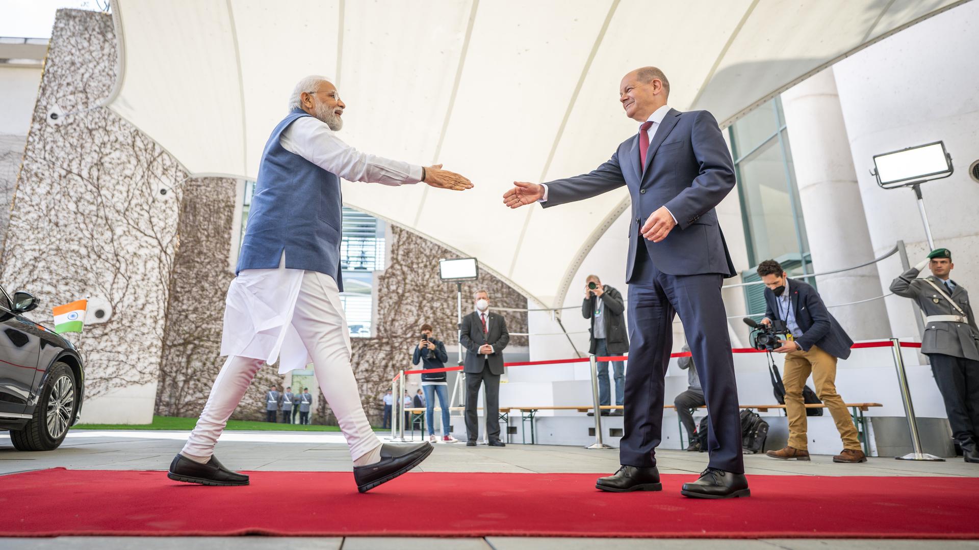 Deutsch-indische Regierungskonsultationen: Bundeskanzler Olaf Scholz begrüßt Narendra Modi, Premierminister von Indien. Die beiden Männer gehen aufeinander mit ausgestreckter Hand zu.