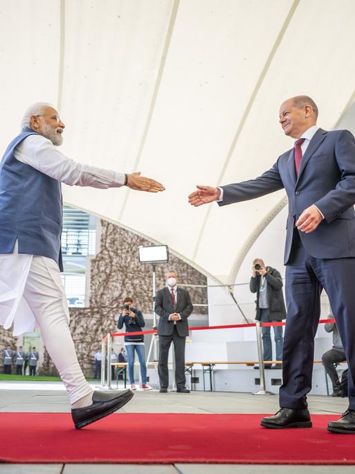 Deutsch-indische Regierungskonsultationen: Bundeskanzler Olaf Scholz begrüßt Narendra Modi, Premierminister von Indien. Die beiden Männer gehen aufeinander mit ausgestreckter Hand zu.