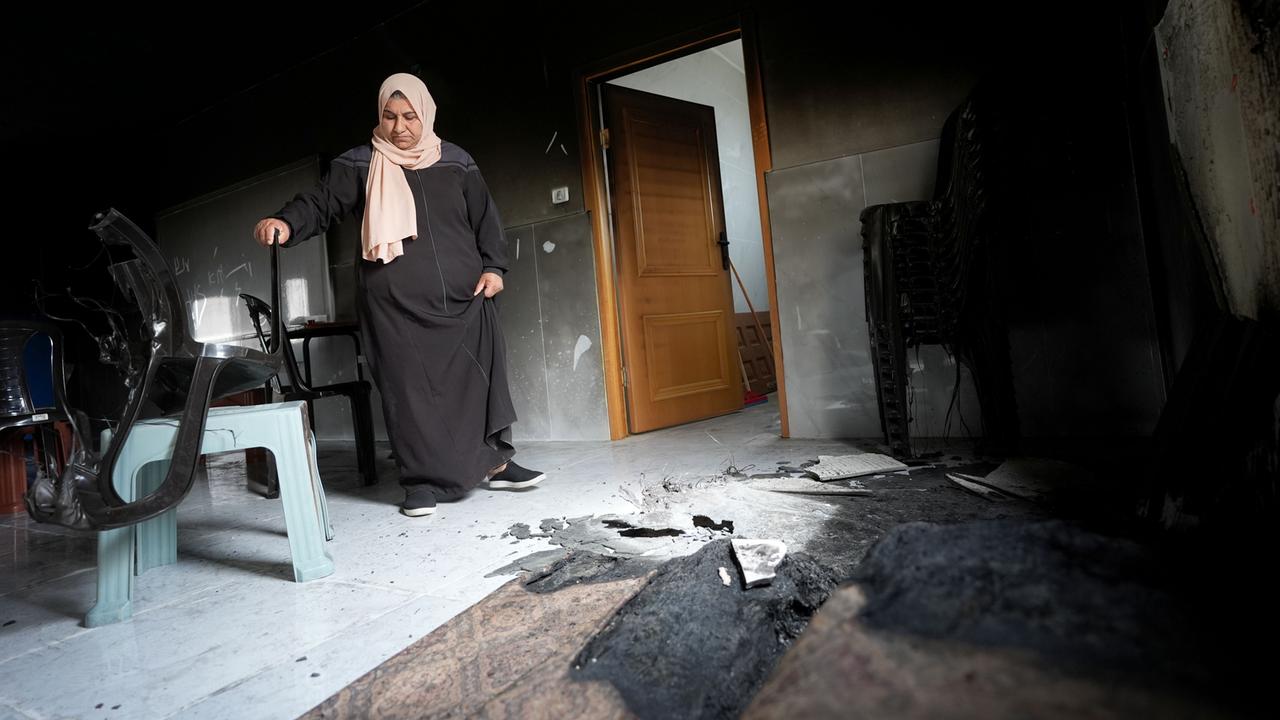 Eine Frau mit Kopftuch steht im Westjordanland vor Brandschäden in ihrem Zuhause. Siedler aus Israel hatten das Dorf Jibiya angegriffen.