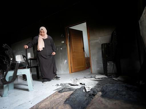 Eine Frau mit Kopftuch steht im Westjordanland vor Brandschäden in ihrem Zuhause. Siedler aus Israel hatten das Dorf Jibiya angegriffen. Eine Frau mit Kopftuch steht im Westjordanland vor Brandschäden in ihrem Zuhause. Siedler aus Israel hatten das Dorf Jibiya angegriffen.