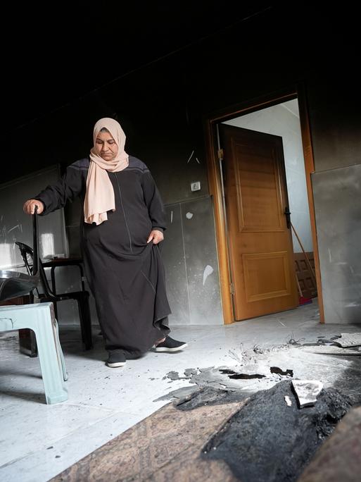 Eine Frau mit Kopftuch steht im Westjordanland vor Brandschäden in ihrem Zuhause. Siedler aus Israel hatten das Dorf Jibiya angegriffen. Eine Frau mit Kopftuch steht im Westjordanland vor Brandschäden in ihrem Zuhause. Siedler aus Israel hatten das Dorf Jibiya angegriffen.