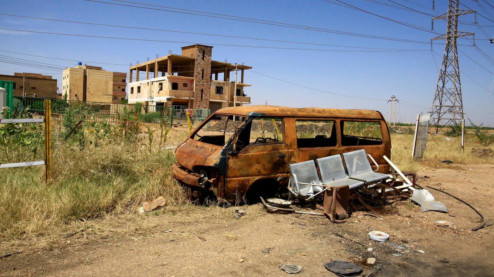 Ein zerstörtes Fahrzeug vor einem zerstörten Haus in Sudan. 