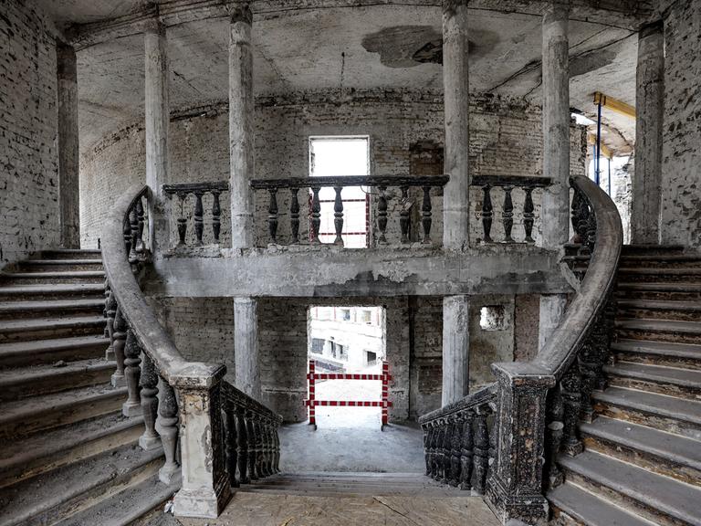 Blick in den Treppenaufgang des zerstörten Theaters von Mariupol mit Brandspuren und Schutt auf den Stufen