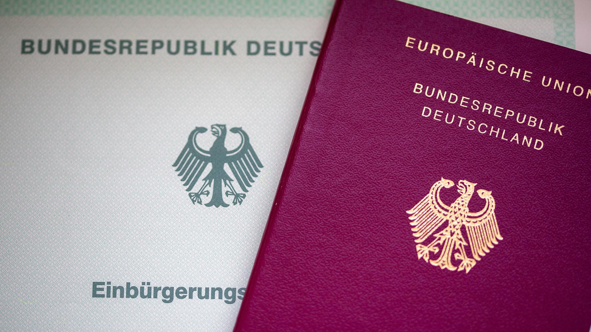 Eine Einbürgerungsurkunde der Bundesrepublik Deutschland (l) und ein deutscher Reisepass liegen auf einem Tisch. 