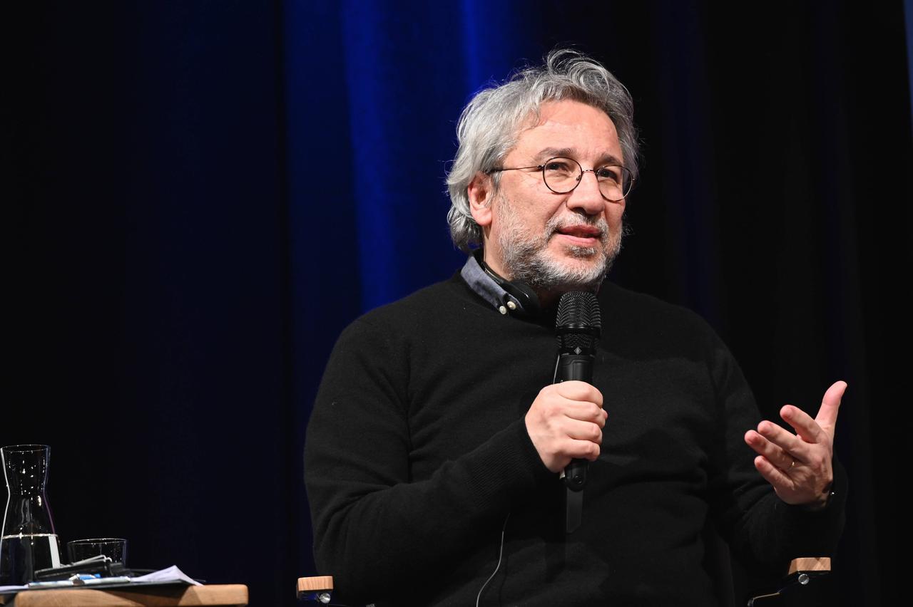 Der türkische Journalist Can Dündar steht mit einem Mikrofon in der Hand vor einem schwarzen-blauen Vorhang Der türkische Journalist Can Dündar steht mit einem Mikrofon in der Hand vor einem schwarzen-blauen Vorhang