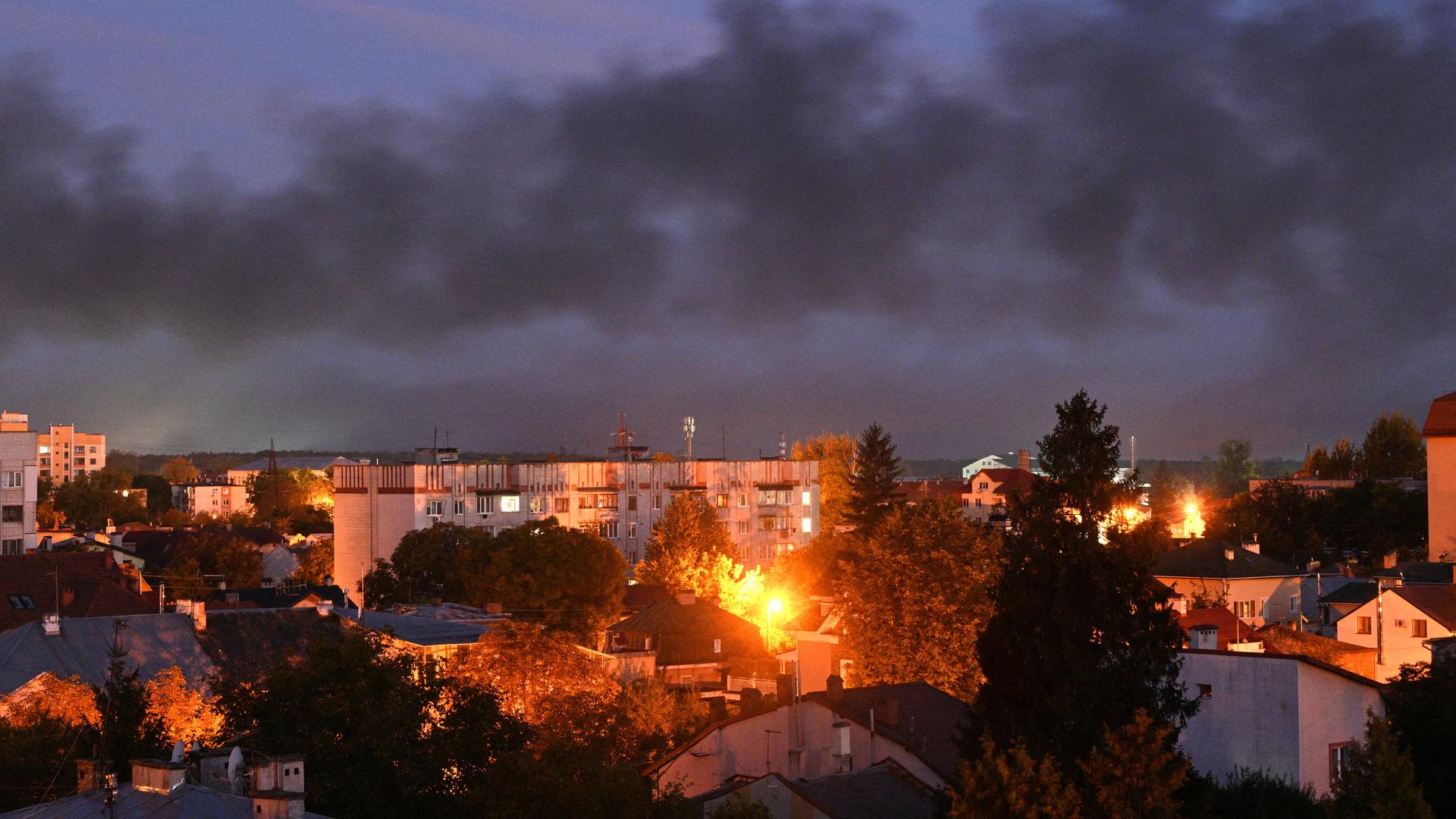 Blick auf die ukrainische Stadt Lwiw in der Dämmerung. Flammen schlagen aus einem Viertel, über der Stadt hängt dunkler Rauch. Blick auf die ukrainische Stadt Lwiw in der Dämmerung. Flammen schlagen aus einem Viertel, über der Stadt hängt dunkler Rauch.