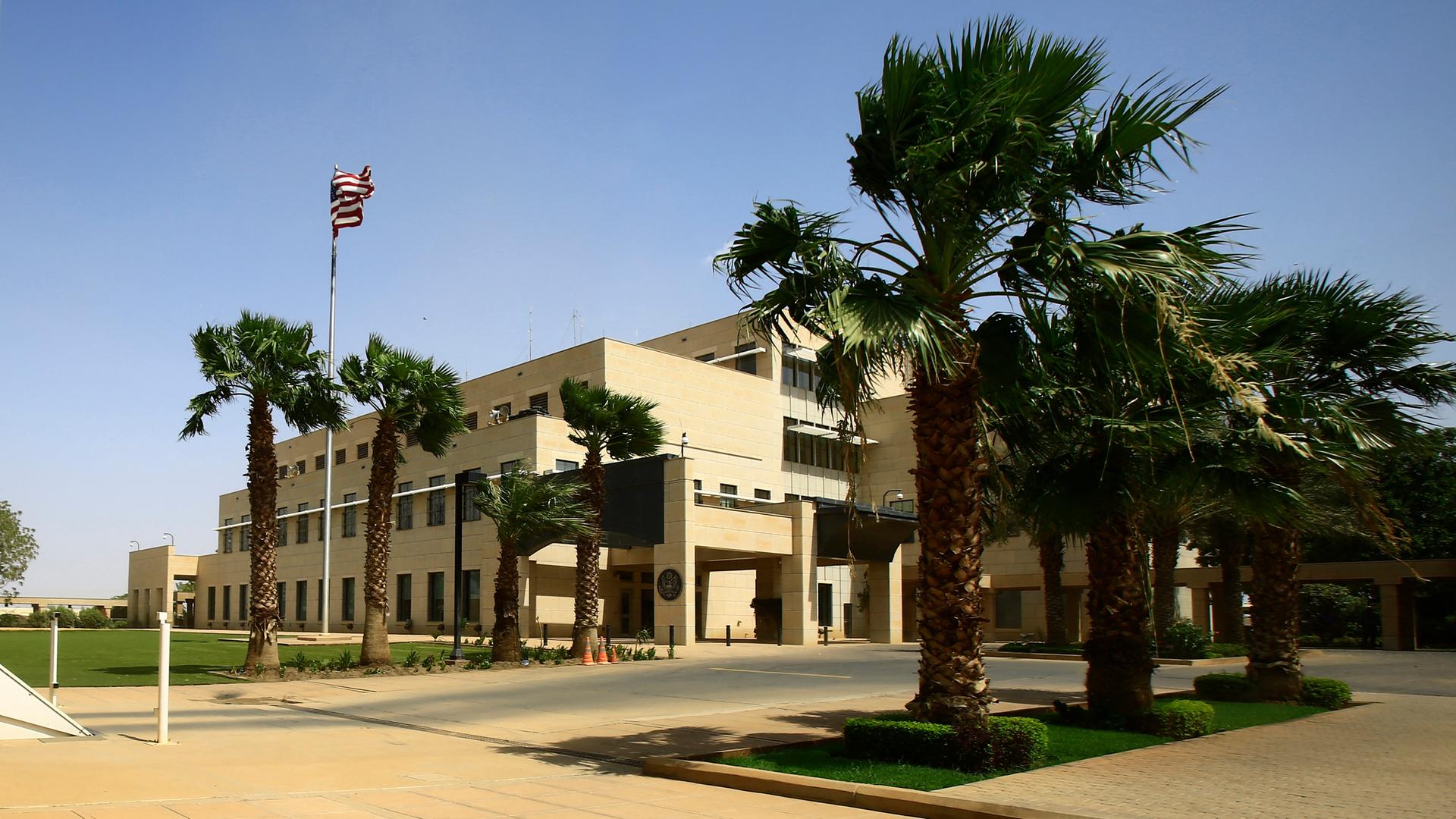 Das Gebäude der US-Botschaft in der sudanesischen Hauptstadt Khartum. Vor dem Gebäude stehen mehrere Palmen und es weht eine amerikanische Flagge im Wind.