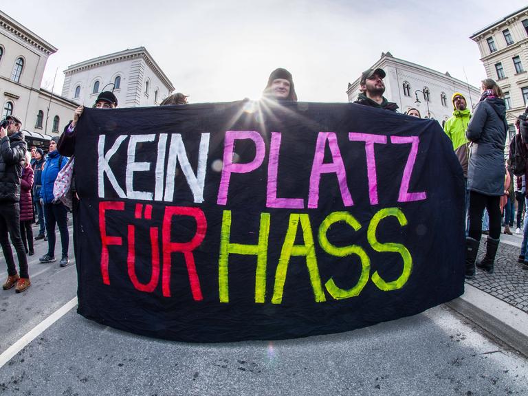 Ein Plakat auf einer Demo für die Demokratie in München wird gezeigt. Auf schwarzen Hintergrund steht in großen, bunten Lettern "KEIN PLATZ FÜR HASS". Ein Plakat auf einer Demo für die Demokratie in München wird gezeigt. Auf schwarzen Hintergrund steht in großen, bunten Lettern "KEIN PLATZ FÜR HASS".