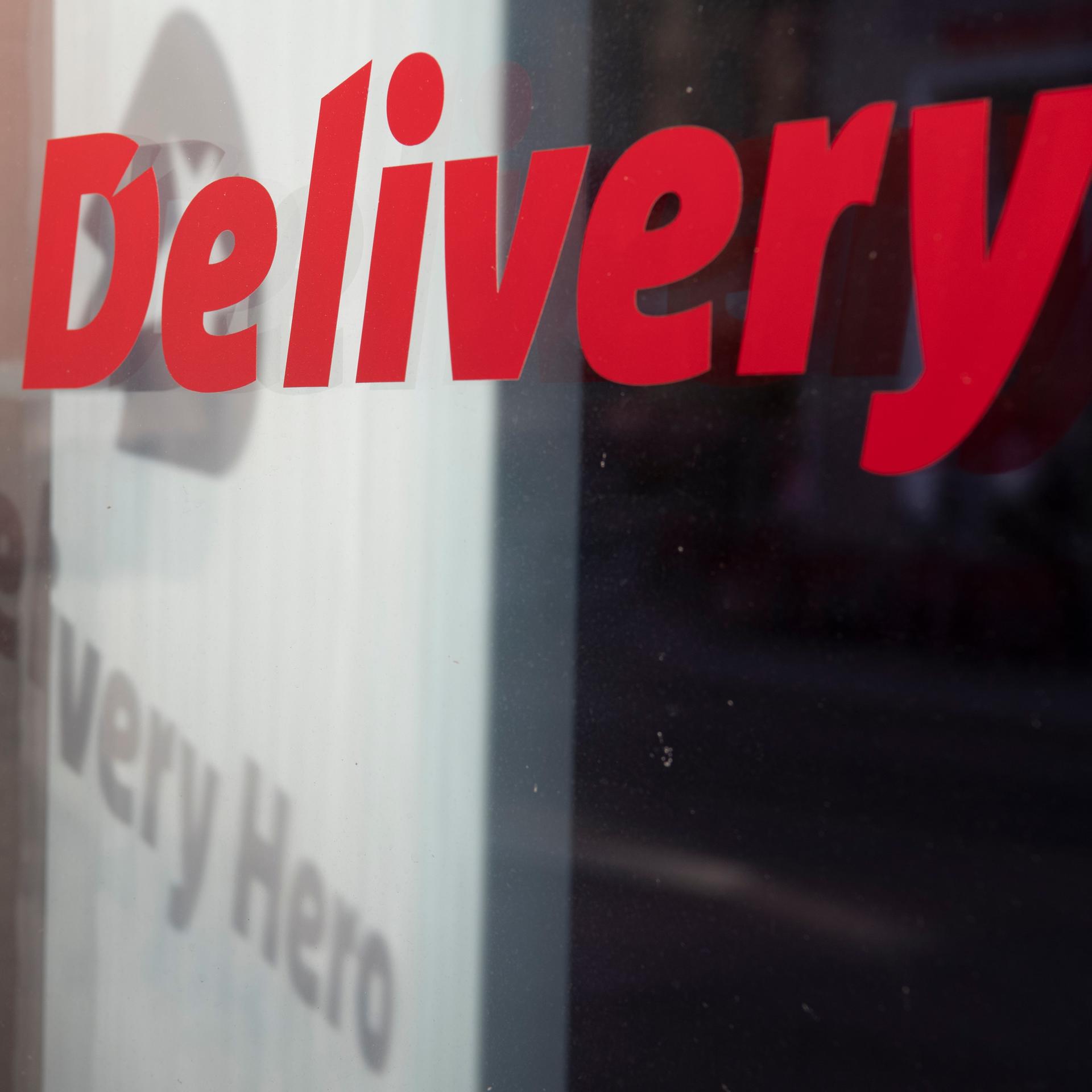 Das Logo und der Schriftzug des Essenslieferdienstes Delivery Hero spiegelt sich in einer Fensterscheibe am Firmensitz des Unternehmens in Berlin. 