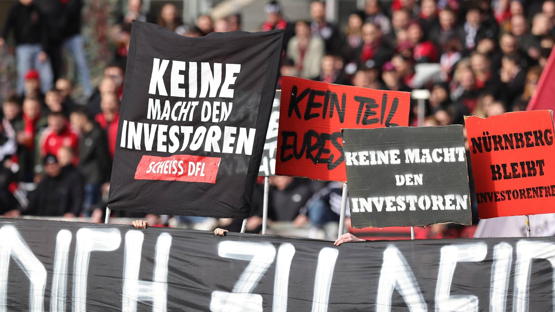 Fans des 1. FC Nürnberg halten Schilder gegen den DFL-Investor hoch.