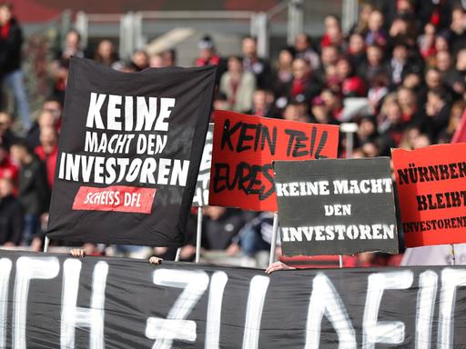 Fans des 1. FC Nürnberg halten Schilder gegen den DFL-Investor hoch.