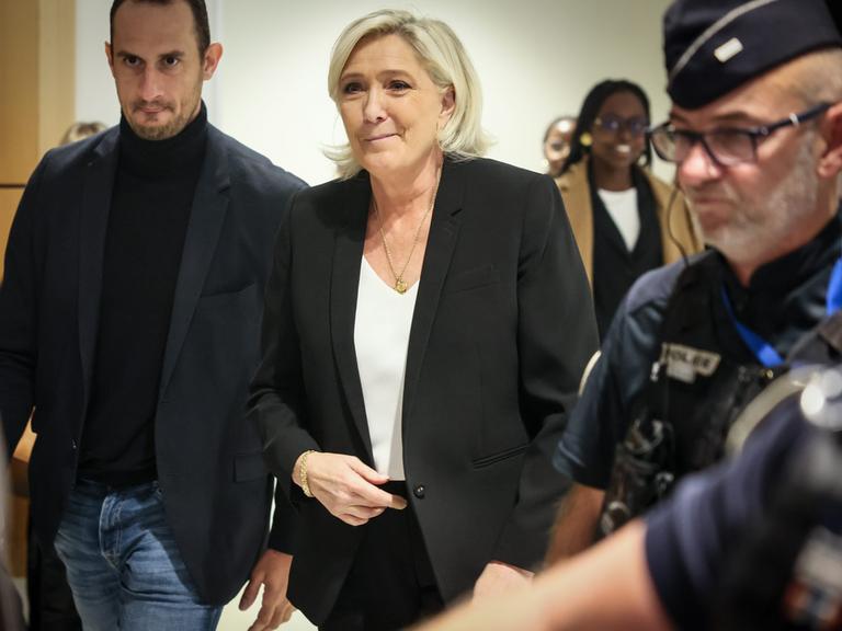 Die Politikerin Marine Le Pen von der rechtsnationalen Partei Rassemblement National in dunkler Kleidung und mit ernstem Gesicht auf dem Weg in den Gerichtssaal in Paris.