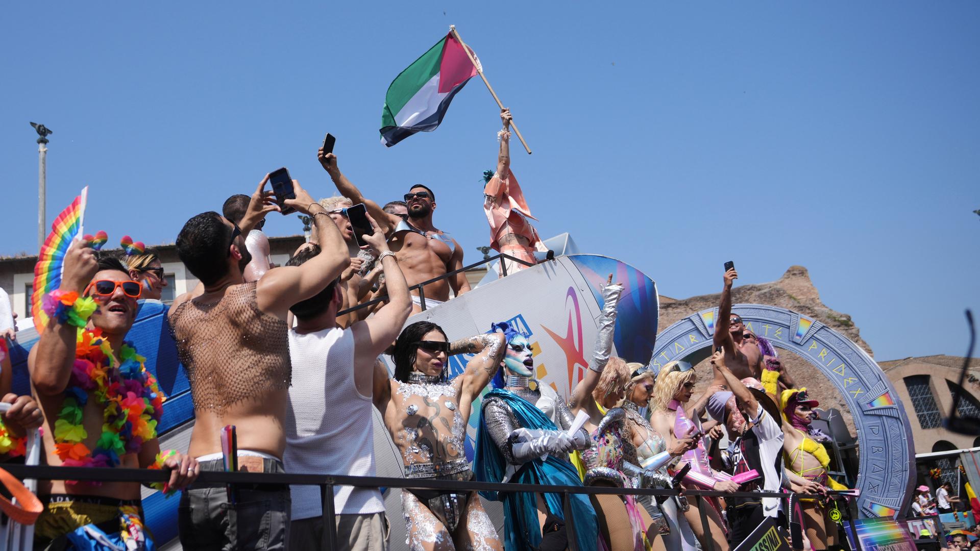 Feiernde bei der Roma-Pride-Parade 2025. Ein Teilnehmer hält eine palästinensische Flagge hoch.