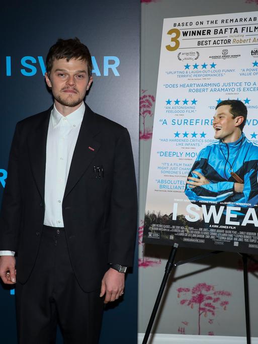 Der Schauspieler Robert Aramayo vor dem Filmplakat von "I Swear", einem Film über einen Mann mit Tourette (April 2026)