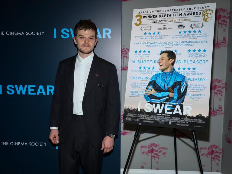 Der Schauspieler Robert Aramayo vor dem Filmplakat von "I Swear", einem Film über einen Mann mit Tourette (April 2026)