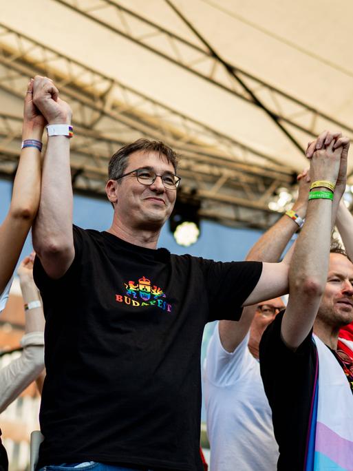 Gergely Karácsony steht während der Pride gemeinsam mit Aktivisten auf der Bühne. Er trägt ein schwarzes Shirt, auf dem in Regenbogenfarben "Budapest" steht.