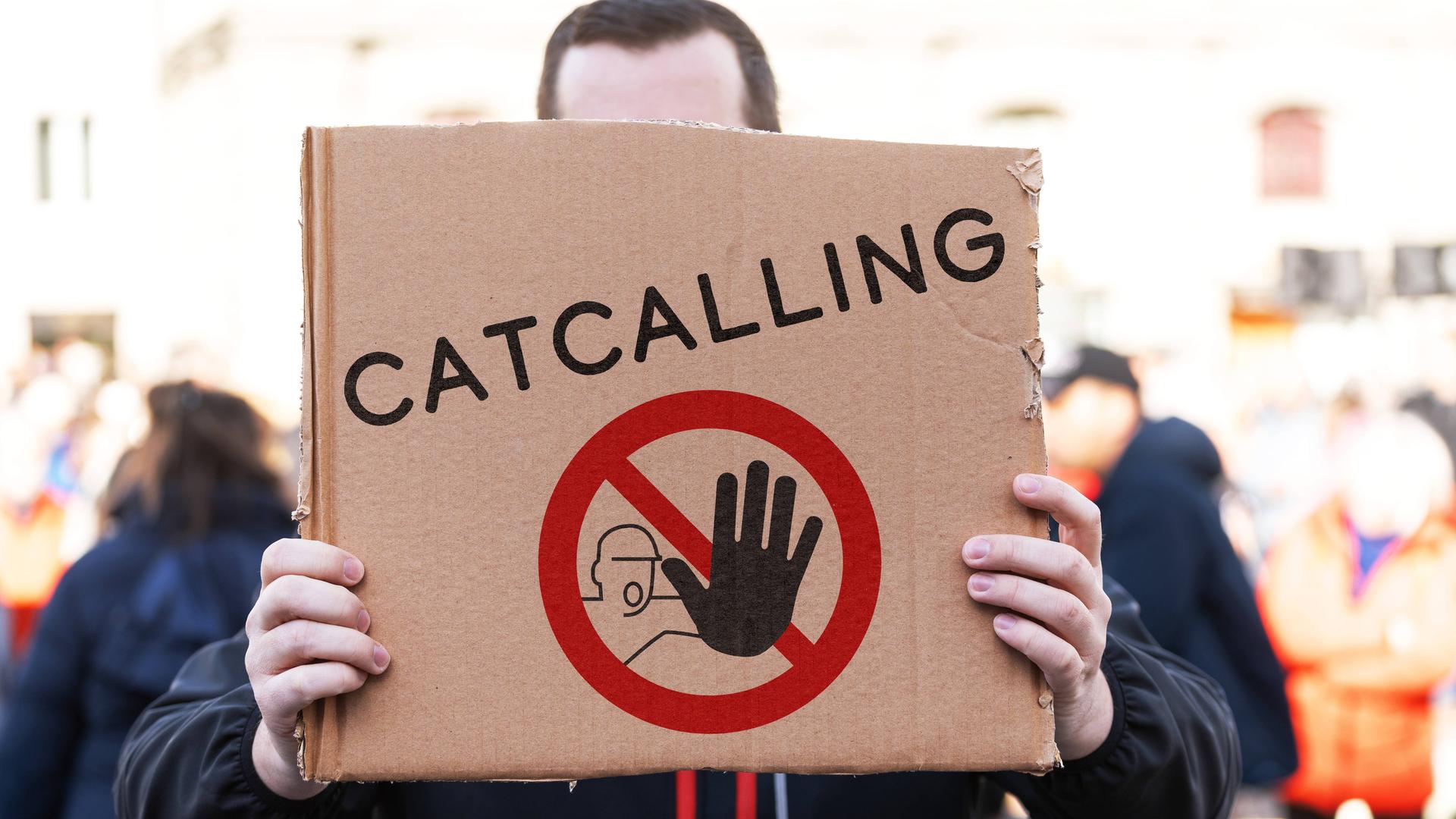 Ein Demonstrant hält ein Pappschild mit einem Stopp-Symbol und der Aufschrift: Catcalling