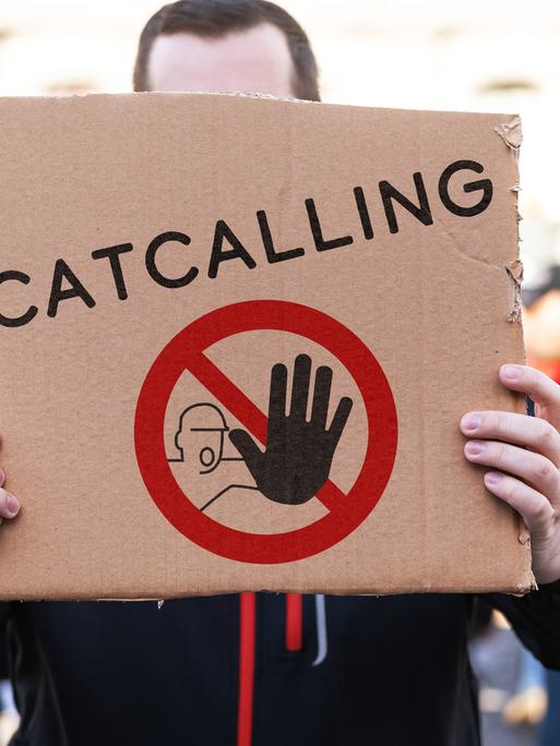 Ein Demonstrant hält ein Pappschild mit einem Stopp-Symbol und der Aufschrift: Catcalling