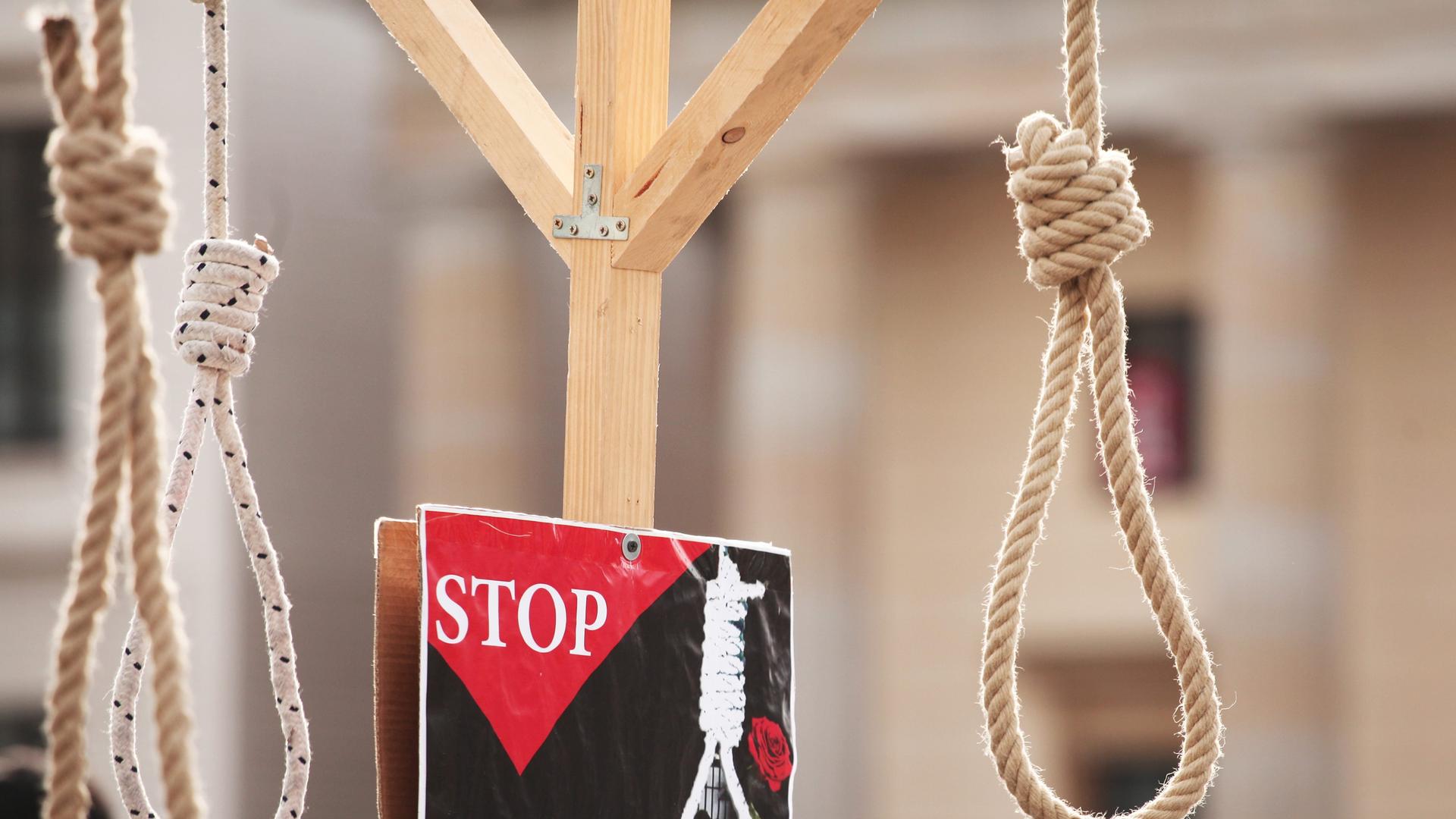 Bei einer Aktion gegen Folter und Todesstrafe im Iran vor dem Brandenburger Tor in Berlin hängen symbolisch Henkersschlingen von einem Galgen. Daneben ist ein Schild mit einer Rose, einer Schlinge und der Aufschrift "Stop" zu sehen. Bei einer Aktion gegen Folter und Todesstrafe im Iran vor dem Brandenburger Tor in Berlin hängen symbolisch Henkersschlingen von einem Galgen. Daneben ist ein Schild mit einer Rose, einer Schlinge und der Aufschrift "Stop" zu sehen.