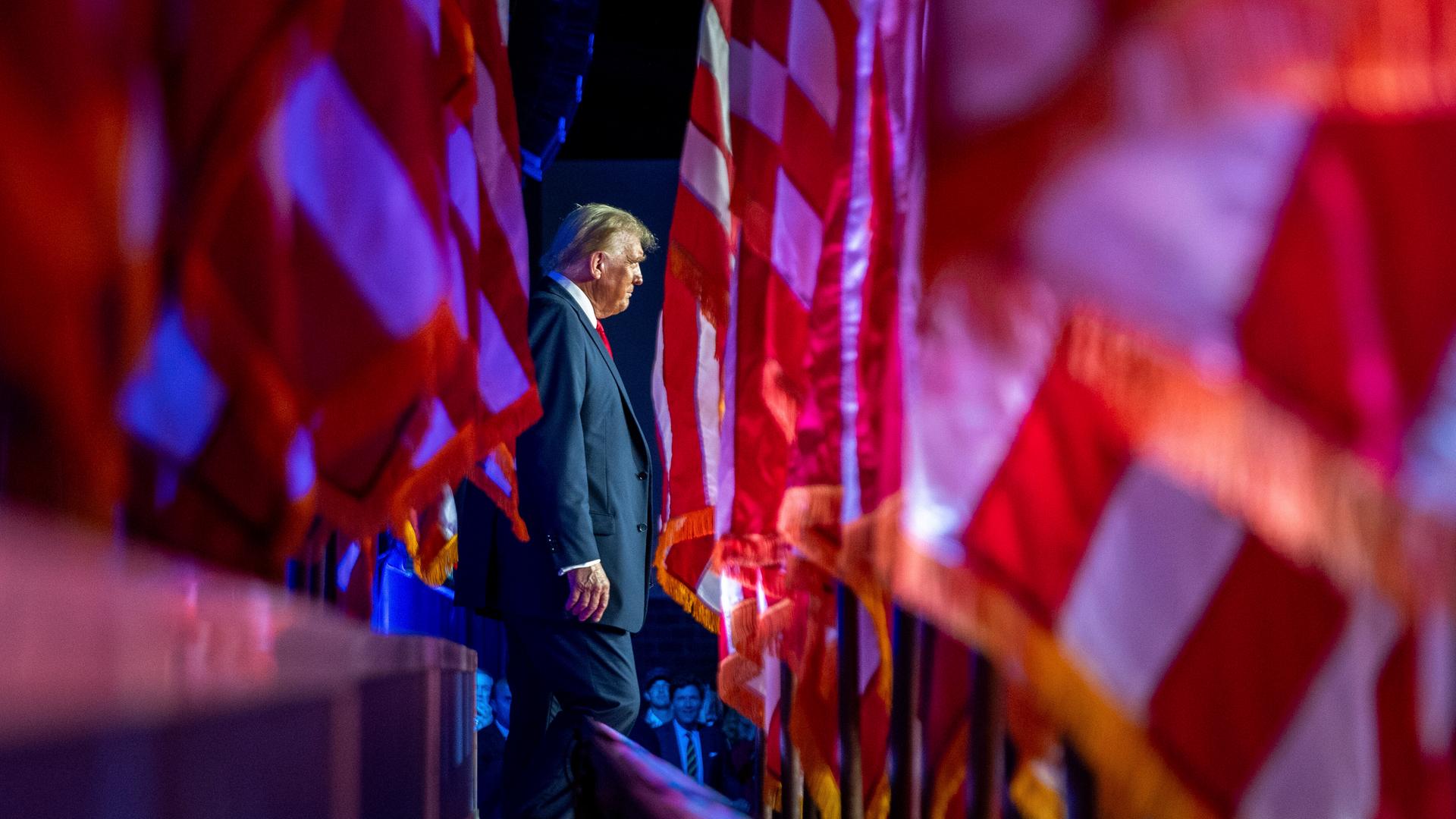 Der US-Präsident Donald Trump in West Palm Beach, Florida bei einer Wahlnacht-Party 2024, er tritt durch ein Meer von amerikanischen Flaggen. Der US-Präsident Donald Trump in West Palm Beach, Florida bei einer Wahlnacht-Party 2024, er tritt durch ein Meer von amerikanischen Flaggen.