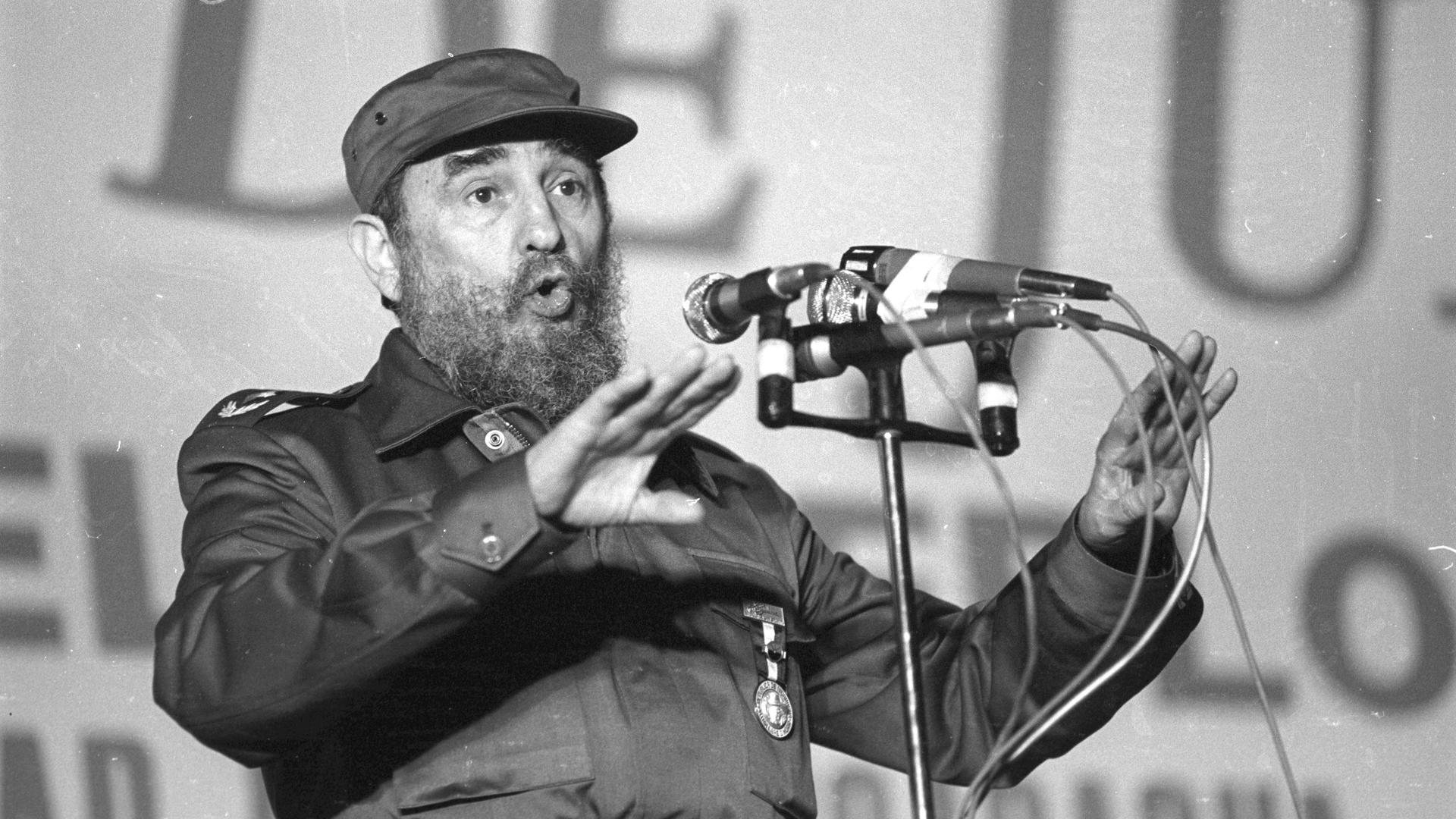 Fidel Castro trägt Militäruniform, steht bei einem politischem Auftritt am Mikrofon und spricht. Fidel Castro trägt Militäruniform, steht bei einem politischem Auftritt am Mikrofon und spricht.