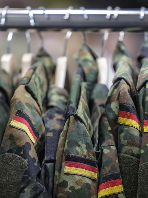 Feldjacken der Bundeswehr hängen auf Kleiderbügeln an einer Stange. 