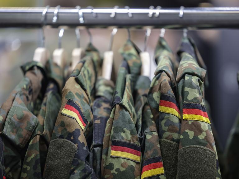 Feldjacken der Bundeswehr hängen auf Kleiderbügeln an einer Stange. 