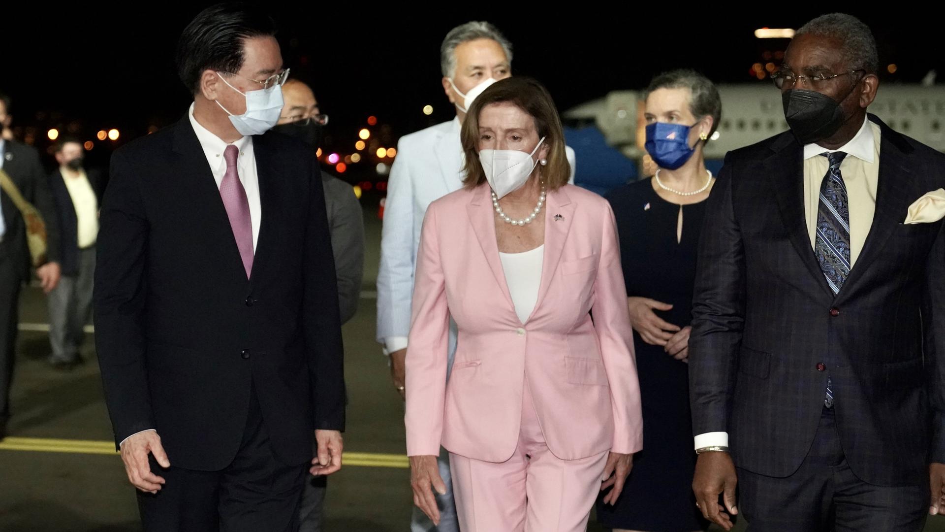 Nancy Pelosi, im blassrosa Kostüm, wird von Taiwans Außenminister Joseph Wu am Flughafen empfangen. Wu, Pelosi und ihre Mitarbeiterinnen und Mitarbeiter tragen Corona-Schutzmasken.