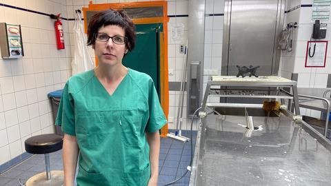 Die Rechtsmedizinerin Sarah Kölzer steht in einem Gerichtsmedizinischen Institut, sie trägt einen grünen Operationskittel.