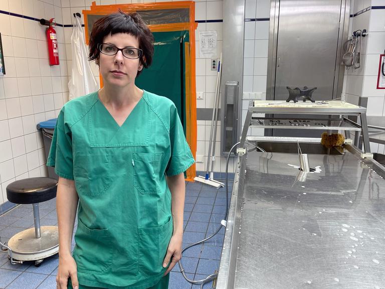 Die Rechtsmedizinerin Sarah Kölzer steht in einem Gerichtsmedizinischen Institut, sie trägt einen grünen Operationskittel.