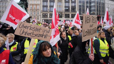 Menschen protestieren mit Fahnen und Plakaten während einer Kundgebung der Gewerkschaft Verdi vor der Finanzbehörde in Hamburg.