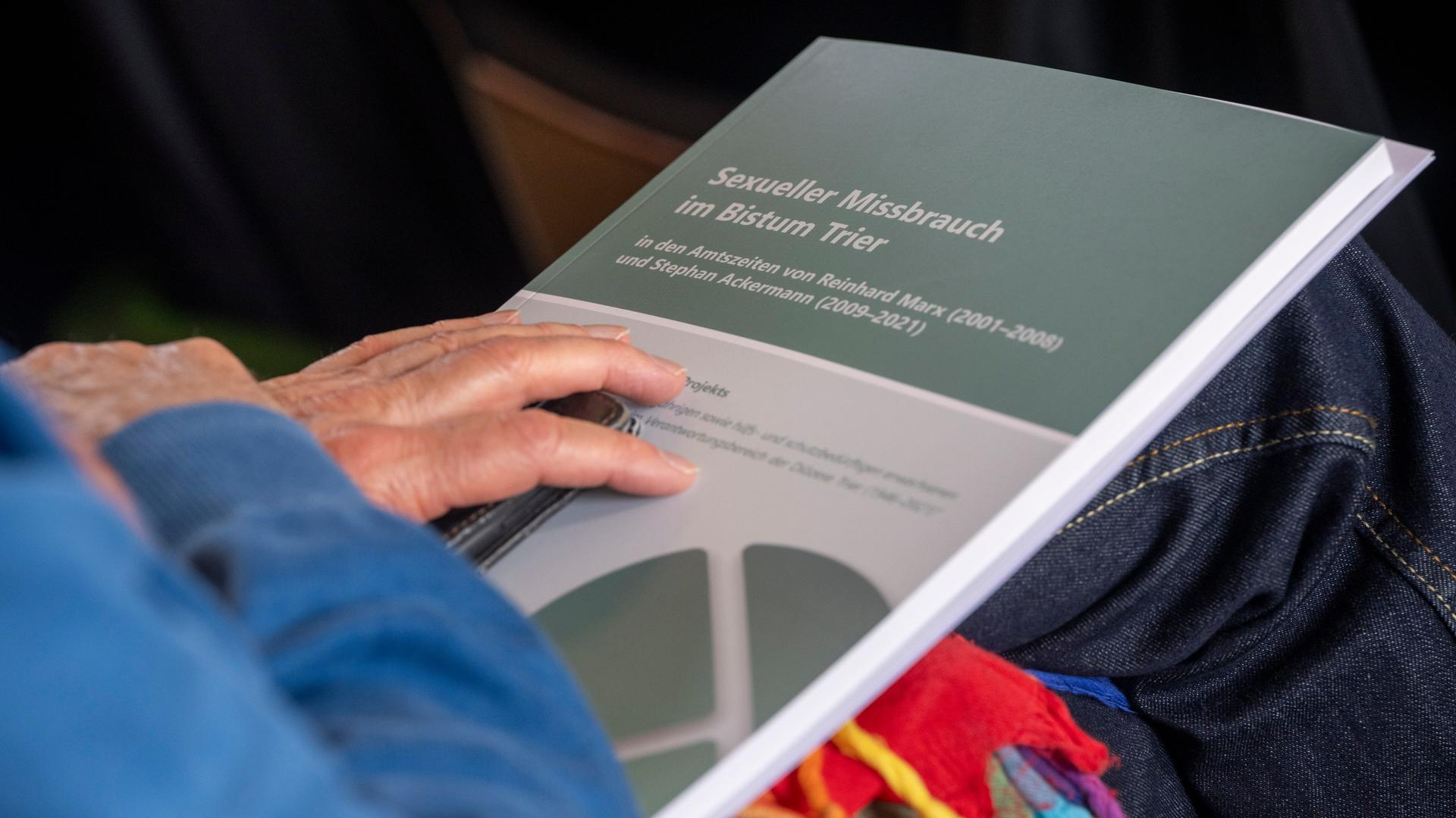 Die Hand eines Besucher der Pressekonferenz zum dritten Zwischenbericht über sexuellen Missbrauch im Bistum Trier liegt auf den Unterlagen Die Hand eines Besucher der Pressekonferenz zum dritten Zwischenbericht über sexuellen Missbrauch im Bistum Trier liegt auf den Unterlagen