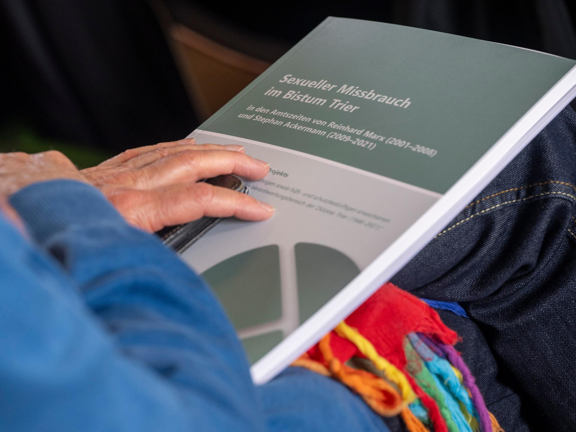 Die Hand eines Besucher der Pressekonferenz zum dritten Zwischenbericht über sexuellen Missbrauch im Bistum Trier liegt auf den Unterlagen