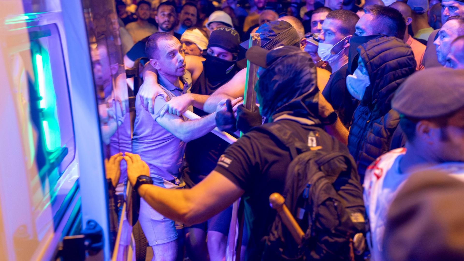 Demonstranten in Serbien: Gewalt zwischen Gegnern und Anhängern der Regierung. Einige der Demonstranten sind schwarz gekleidet und vermummt. Man sieht das Ende von einem Base-Ball-Schläger in einem Ruck-Sack. 
