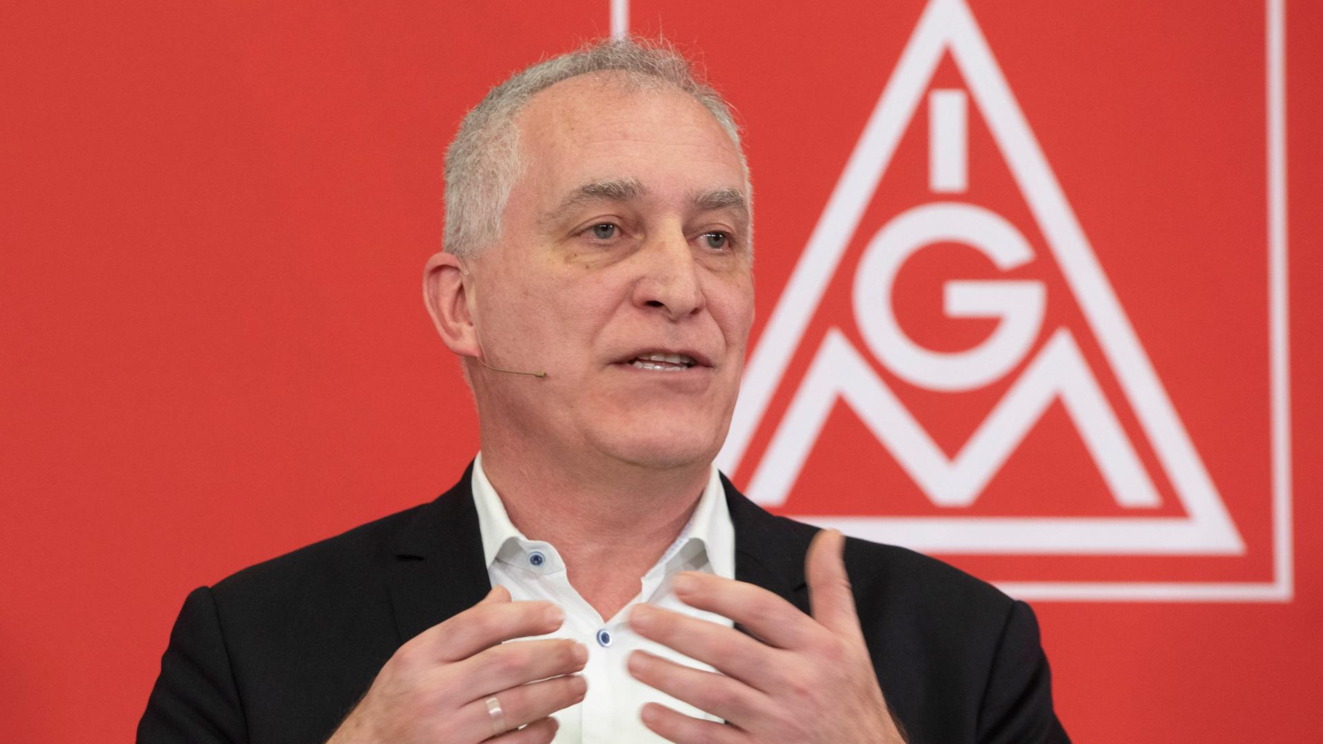 Jürgen Kerner, der Zweite Vorsitzende der Gewerkschaft IG Metall, gestikuliert, während er spricht. Hinter ihm an der Wand ist das Logo der IG Metall.