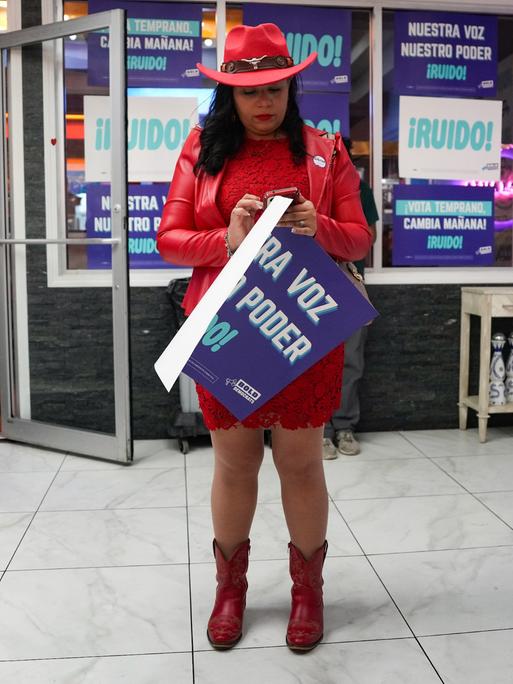 Die hispanische Bürgerrechtlerin Judy Castillo schaut während einer von BOLD DEMOCRATS in Houston veranstalteten Wahlkampfveranstaltung auf ihr Handy. Im Hintergrund: Schilder mit spanischen Losungen "Nuestro Voz, Nuestro Poder"