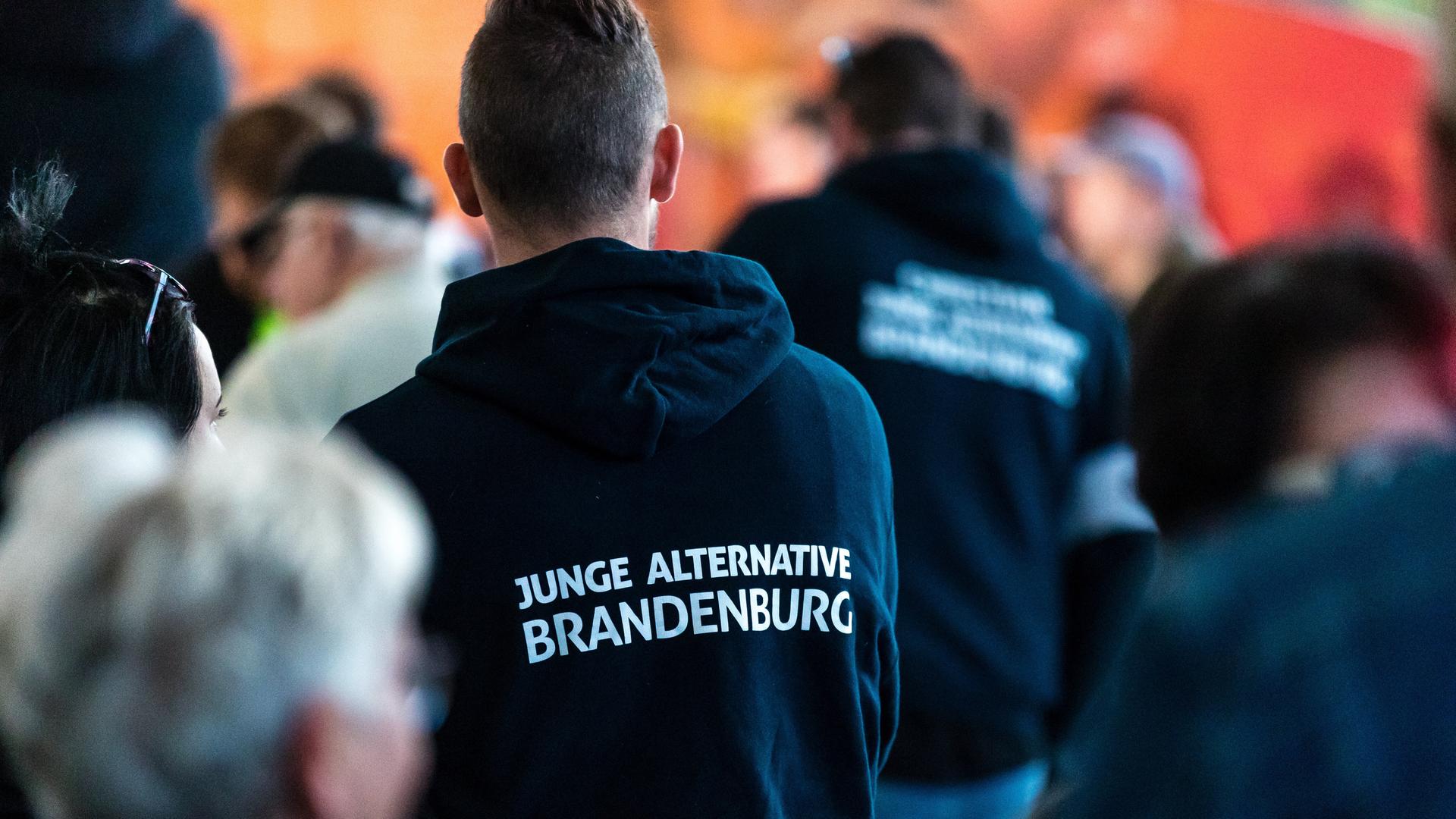 Teilnehmer einer Wahlkampfveranstaltung tragen Kleidung mit der Aufschrift "Junge Alternative Brandenburg".  