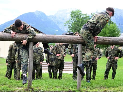 Jägerkaserne in Berchtesgaden/Bischofswiesen: Junge Männer und Frauen in Flecktarn-Overalls balancieren auf Holzbohlen.