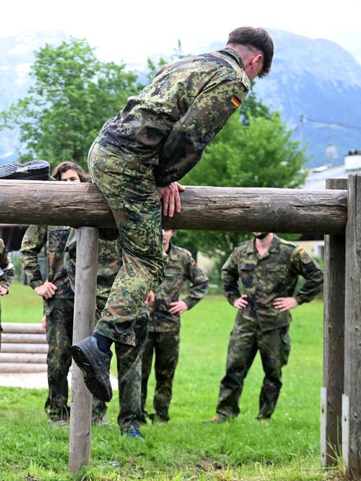 Jägerkaserne in Berchtesgaden/Bischofswiesen: Junge Männer und Frauen in Flecktarn-Overalls balancieren auf Holzbohlen.