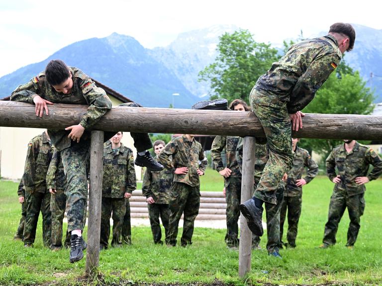 Jägerkaserne in Berchtesgaden/Bischofswiesen: Junge Männer und Frauen in Flecktarn-Overalls balancieren auf Holzbohlen.