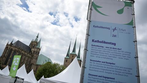Eine große Informationssäule mit Hinweis auf den Deutschen Katholikentag steht auf dem Domplatz in Erfurt. Im Hintergrund der Dom. 