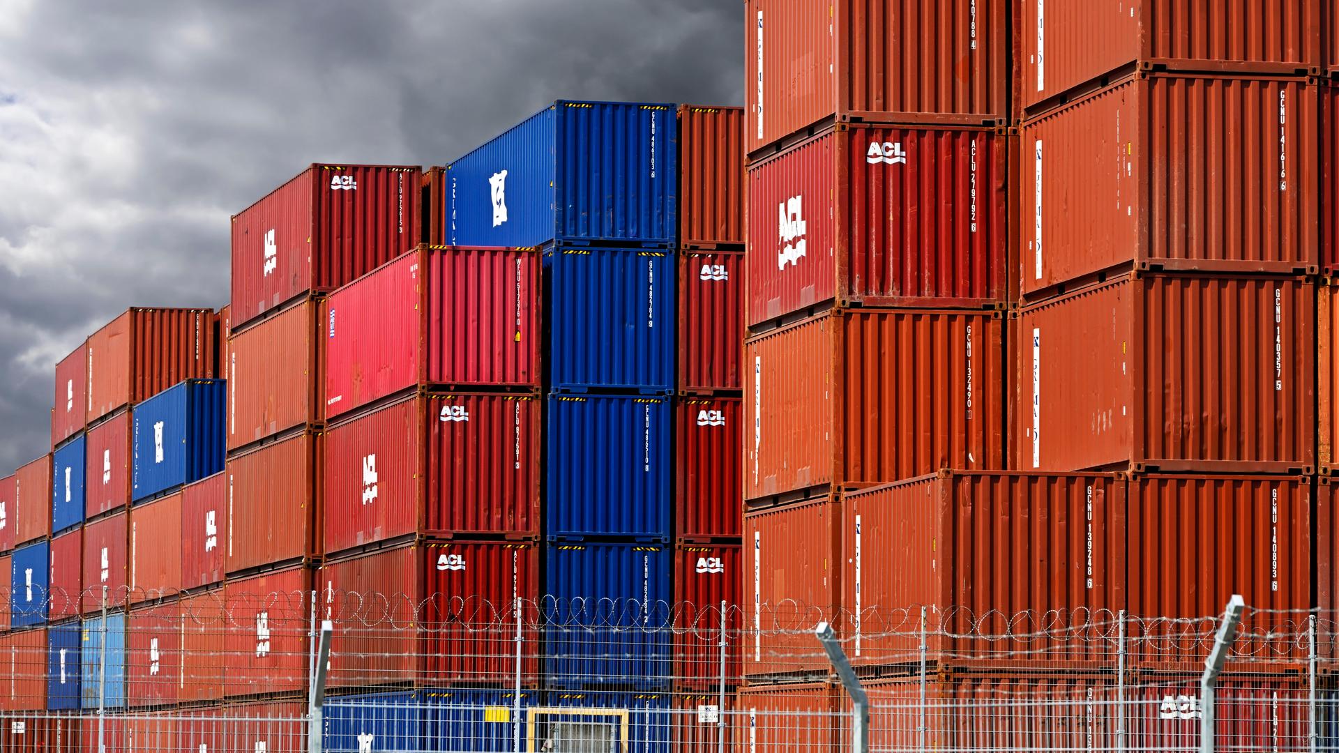 Gestapelte bunte Container im Hafengebiet von Hamburg vor dunklen Wolken