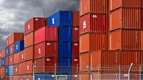 Gestapelte bunte Container im Hafengebiet von Hamburg vor dunklen Wolken