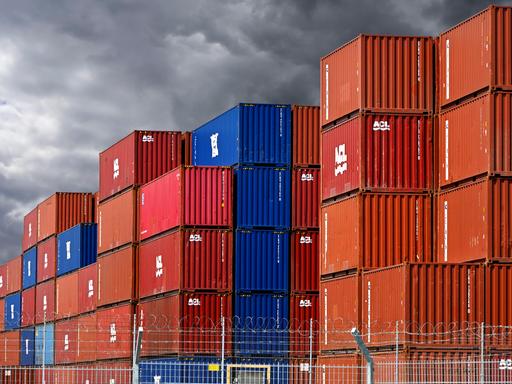 Gestapelte bunte Container im Hafengebiet von Hamburg vor dunklen Wolken