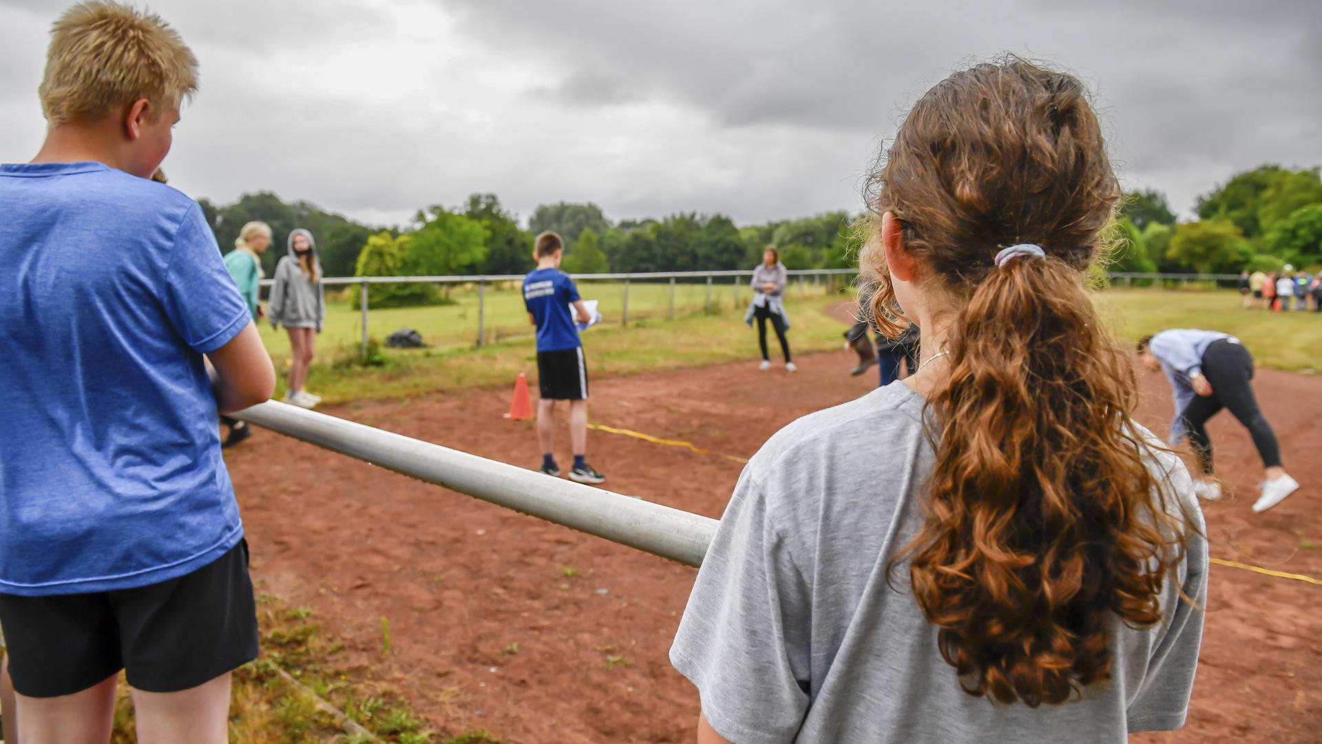 Jugendliche beobachten einen Wettkampf auf einem Sportplatz. Jugendliche beobachten einen Wettkampf auf einem Sportplatz.