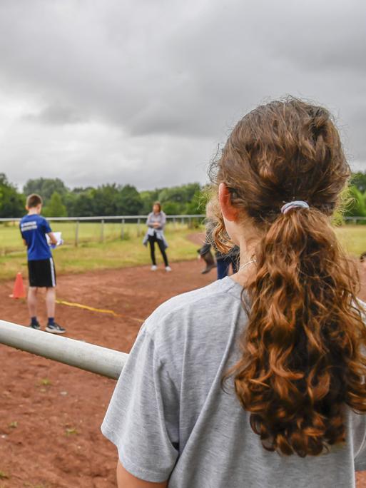 Jugendliche beobachten einen Wettkampf auf einem Sportplatz. Jugendliche beobachten einen Wettkampf auf einem Sportplatz.